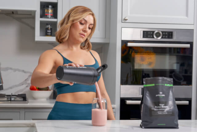 Woman drinking protein shake in workout clothes